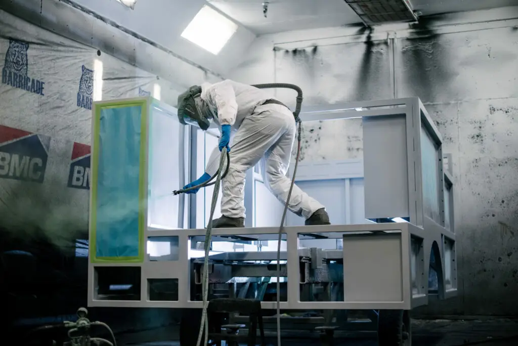 Man BME Employee on top of the fire body spraying green paint onto the body